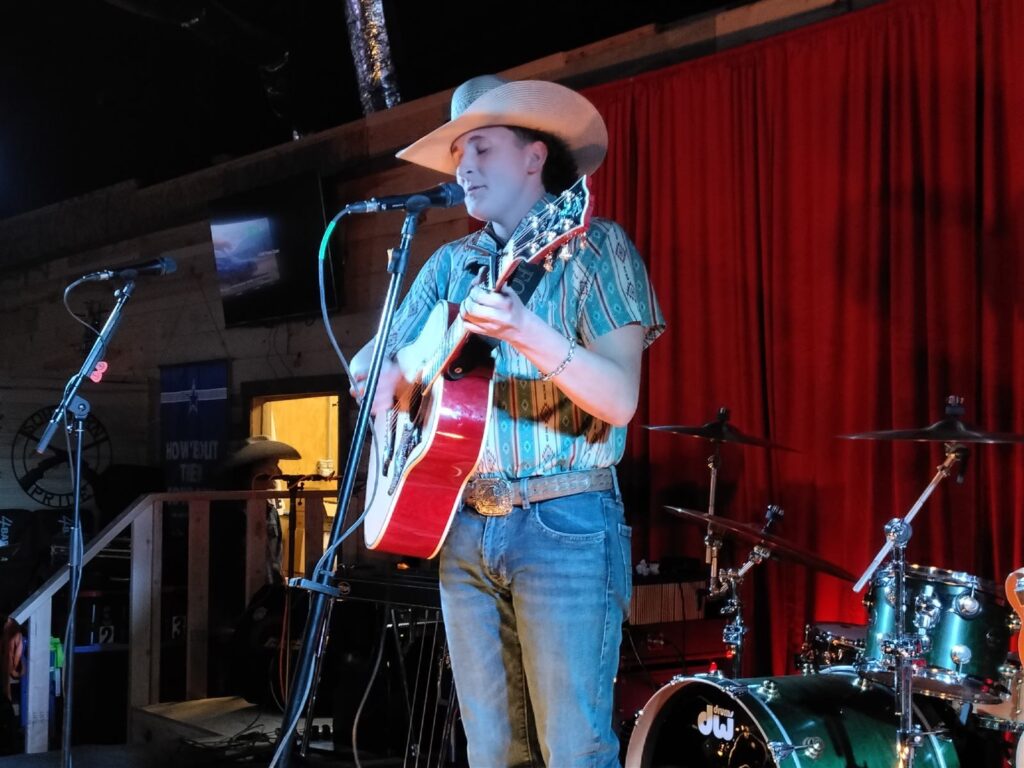 Performer with guitar on The 156 stage